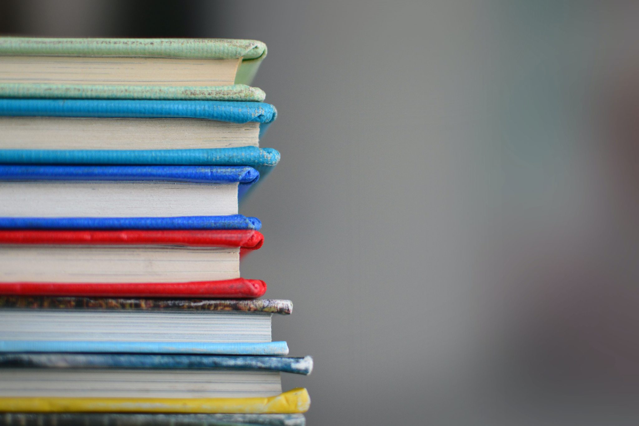 Stack of multicolored books. This page contains information about grants for writers and print projects.